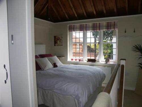 a bedroom with a bed and two windows at The Gazebo in Winchelsea in Winchelsea