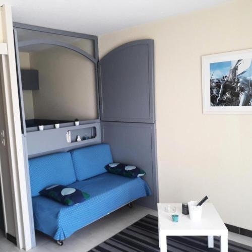 Cette petite chambre dispose d'un canapé bleu et d'une table. dans l'établissement Hyeres Parc - maeva Home - Studio 4 Personnes Confort MAE-5104, à Hyères