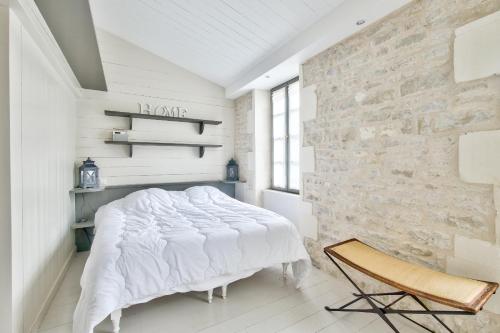 une chambre avec un lit blanc et un mur en pierre dans l'établissement Charmante maison pour 2 - 500m de la plage, à La Flotte