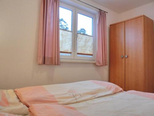 een slaapkamer met een bed en een raam met roze gordijnen bij Ferienwohnung KWF6bEG in Graal-Müritz