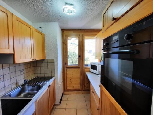 La cuisine est équipée d'un évier et d'un réfrigérateur noir. dans l'établissement Résidence Pelvoux - Appartement pour 8 au coeur des Ménuires et ski aux pieds MAE-4394, aux Menuires