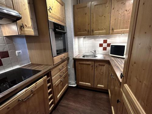 une cuisine avec des armoires en bois et un évier dans l'établissement Résidence Pelvoux - Appartement pour 8 personnes exposé Sud et Nord MAE-4434, aux Menuires