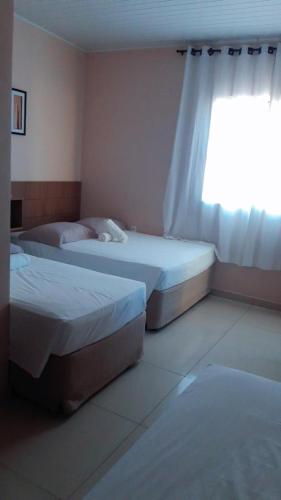 two beds in a room with a window at HOTEL CAROLINE in Timon