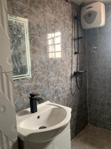 a bathroom with a sink and a shower with a window at California Luxury Hotel & Suite in Ibadan