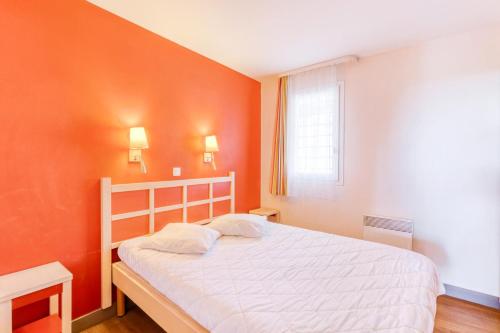 - une chambre avec des murs orange et un lit blanc dans l'établissement Résidence le Village de Cap Esterel - maeva Home - Appartement 2 Pièces 5 Personnes - Confort MAE-1074, à Saint-Raphaël