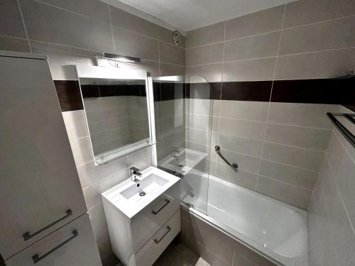 a bathroom with a sink and a mirror and a tub at Résidence Oisans - 2 Pièces pour 6 Personnes 824 in Les Menuires