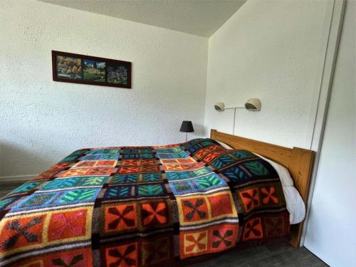 une chambre avec un lit avec une couette colorée dans l'établissement Résidence Aravis - Appartement 6 pers station des 3 Vallées MAE-4834, aux Menuires