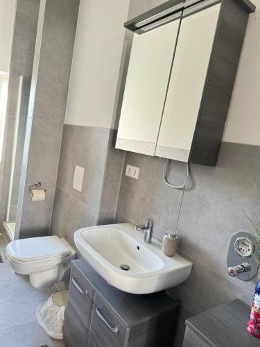 a bathroom with a sink and a toilet and a mirror at Gemütliche Retro Wohnung in Bremerhaven