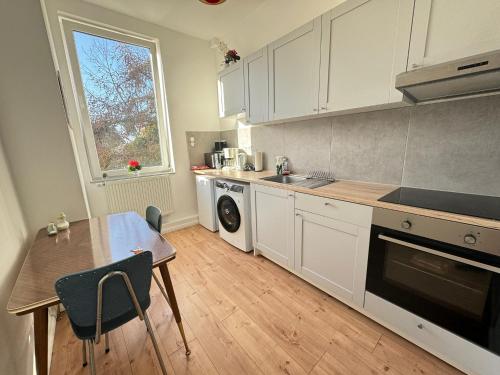 cocina con armarios blancos, mesa y ventana en Gemütliche Retro Wohnung, en Bremerhaven