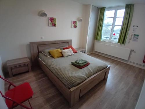 a bedroom with a bed and a red chair at Grand apt lumineux avec extérieur centre bourg 600 m plage proche Omaha Beach et pointe du Hoc in Vierville-sur-Mer