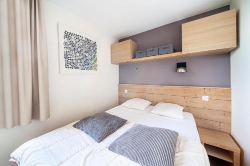 um quarto com uma cama branca e uma cabeceira em madeira em Résidence Plagne Lauze - maeva Home - Appartement super cosy 2 pièces 5 pe 244 em Mâcot La Plagne