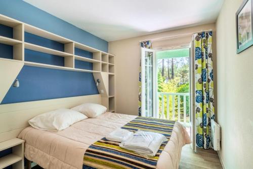 une chambre avec un lit avec un mur bleu dans l'établissement Les Maisons de Lacanau les Pins - maeva Home - Maison 3 Pièces 8 Personnes - Budget MAE-9364, à Lacanau