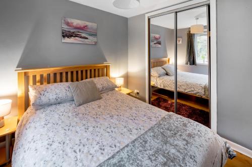 a bedroom with a bed and a mirror at Argyll Apartments - Drimvargie Terrace, Oban in Oban