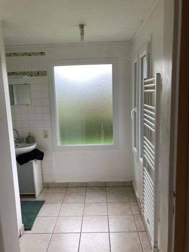 a bathroom with a window and a tiled floor at Cholet 500m du cormier 15 min du puy du fou in Cholet
