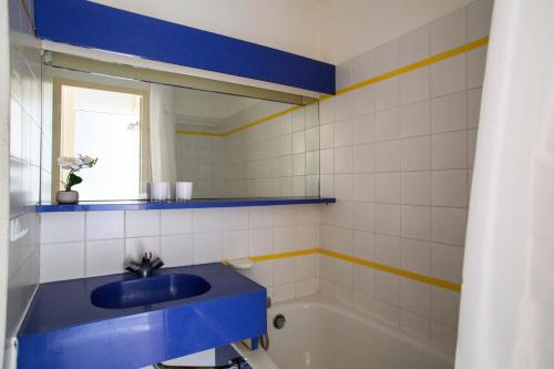 La salle de bains est pourvue d'un lavabo bleu et d'une baignoire. dans l'établissement Résidence Quai des Voiliers 2 - maeva Home - Studio 4 Personnes - Confort - vue sur le Port MAE-7094, à Arzon