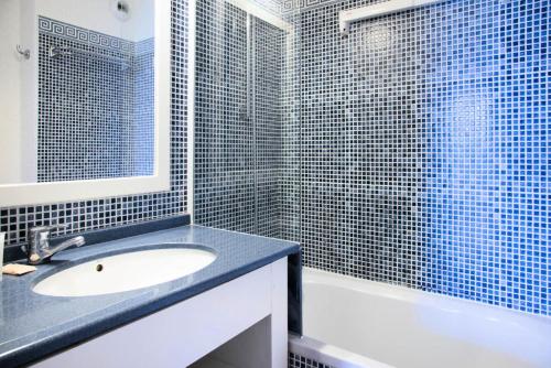 La salle de bains est pourvue d'un lavabo et d'une douche carrelée en bleu. dans l'établissement Résidence Port Bourgenay - maeva Home - Appartement 2 pièces 5 personnes - Sélection MAE-9144, à Talmont-Saint-Hilaire