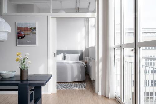 ein Schlafzimmer mit einem weißen Bett, einem Tisch und einem Fenster in der Unterkunft Beach Trail apartments by Daniel&Jacob's in Kopenhagen