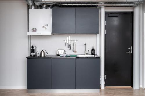 a kitchen with black cabinets and a black door at Beach Trail apartments by Daniel&Jacob's in Copenhagen