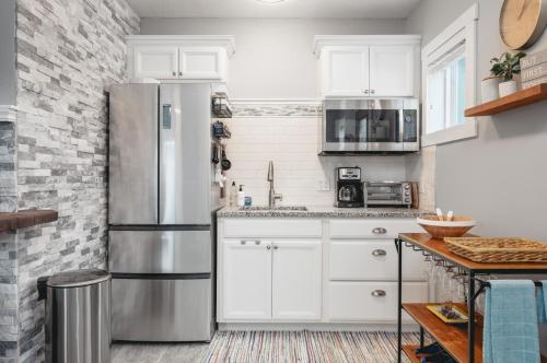 a kitchen with white cabinets and a stainless steel refrigerator at Studio TC Close to Downtown Beaches and Wineries in Traverse City