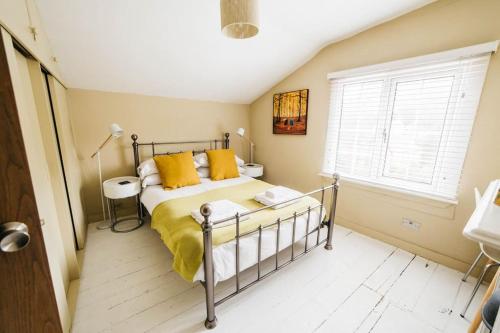 a bedroom with a bed with yellow pillows and a window at Charming & Stylish 2-Bed House - 20 min Walk to Centre in Bath
