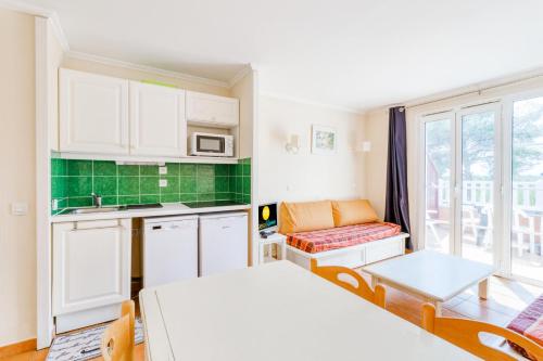 une petite cuisine avec des armoires blanches et une table dans l'établissement Résidence Les Rivages du Lac - maeva Home - Studio 4 Personnes - Sélection MAE-0374, à Drammont