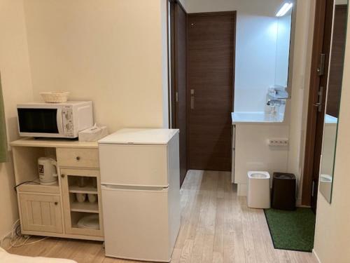 a small kitchen with a microwave and a refrigerator at Asakusa HomeSuites Tokyo in Tokyo