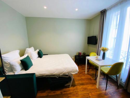 pokój hotelowy z łóżkiem i stołem oraz pokój w obiekcie Les Appartements du Grand Hôtel Clichy Paris w mieście Clichy