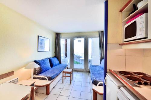 un salon avec un canapé bleu et une cuisine dans l'établissement Résidence Quai des Voiliers 2 - maeva Home - Studio 4 Personnes - Budget - vue sur le Port MAE-4194, à Arzon