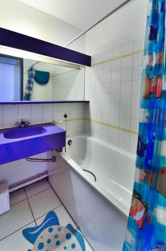 La salle de bains est pourvue d'un lavabo violet et d'une baignoire. dans l'établissement Résidence Quai des Voiliers 2 - maeva Home - Studio 4 Personnes - Budget - vue sur le Port MAE-4194, à Arzon