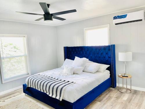 ein blaues Bett in einem weißen Zimmer mit einem Deckenventilator in der Unterkunft Melinas Paradise! in Odessa