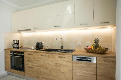 a kitchen with wooden cabinets and a basket of fruit at Beach Front Villa Rhodes Seashell in Gennadi