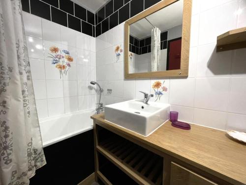 een badkamer met een wastafel, een spiegel en een bad bij Résidence Cote Brune - Studio pour 4 Personnes 114 in Les Menuires