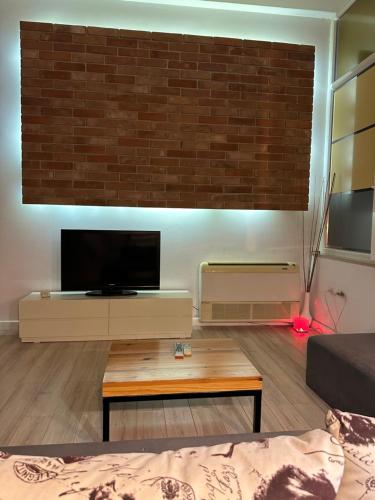 soggiorno con TV a schermo piatto su un muro di mattoni di Town Square Apartment Tirana 4 a Tirana
