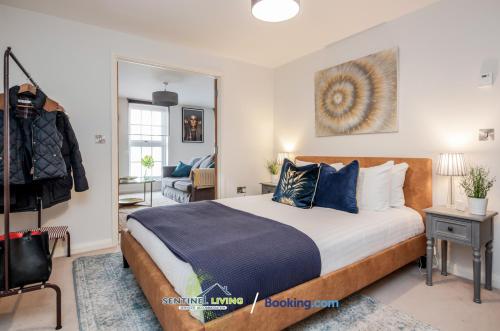 a bedroom with a bed with blue pillows and a mirror at Windsor, 2 Bedroom Apartment By Sentinel Living Short Lets & Serviced Accommodation Windsor Ascot Maidenhead With Free WiFi in Windsor
