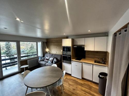 une cuisine et un salon avec une table et un canapé dans l'établissement Résidence Oisans - Studio rénové avec coin montagne, balcon exposé Sud MAE-5174, aux Menuires