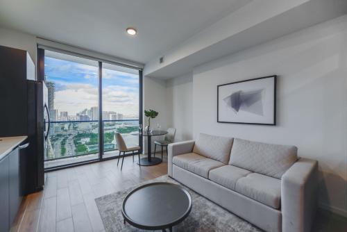 een woonkamer met een bank en een groot raam bij Breathtaking Studio with Bay & City Views in Miami