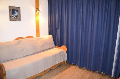 um quarto com uma cama e cortinas azuis em Résidence Lac Du Lou - 2 Pièces pour 4 Personnes 224 em Les Menuires