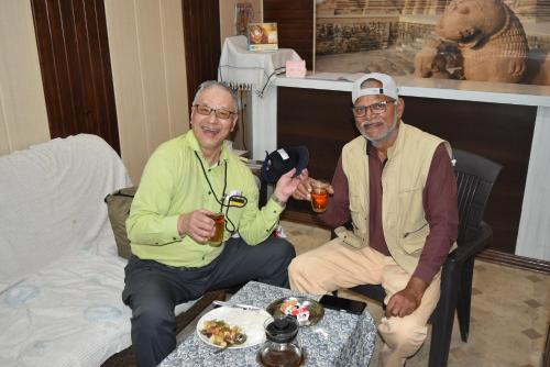 Dos hombres están sentados en una mesa con bebidas. en Hotel Lakeside en Khajurāho