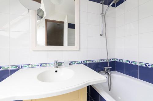 une salle de bain avec un lavabo, une baignoire et un miroir dans l'établissement Port du Crouesty Cap'Océan - maeva Home - Appartement 3 pièces 7 personnes - Sélection - vue sur le Port MAE-5824, à Arzon