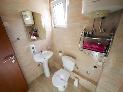 a bathroom with a white toilet and a sink at Marinero Apartments in Kotor