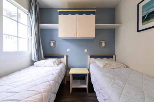 2 lits dans une chambre avec une table et une armoire dans l'établissement Port du Crouesty Cap'Océan - maeva Home - Appartement 2 Pièces 4 Personnes - Sélection MAE-1424, à Arzon