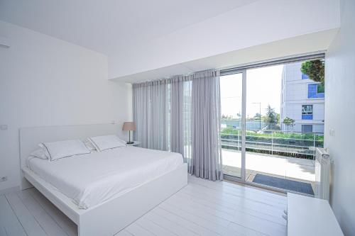 Dormitorio blanco con cama y ventana grande en Spacious VIlla with Swiming Pool and Terrace, en Cascais