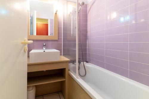 La salle de bains est pourvue de carrelage violet, d'un lavabo et d'une baignoire. dans l'établissement Village Moliets - maeva Home - Appartement 2 Pièces 5 Personnes - Confort MAE-4444, à Moliets-et-Maa