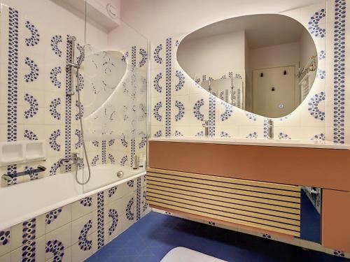 La salle de bains est pourvue de carrelage bleu et blanc et d'un miroir. dans l'établissement Appartement vue mer Juan les Pins, à Antibes