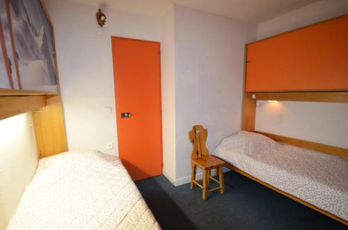 ein kleines Zimmer mit 2 Betten und einem Holzstuhl in der Unterkunft Résidence Chaviere - 2 Pièces pour 4 Personnes 434 in Les Menuires