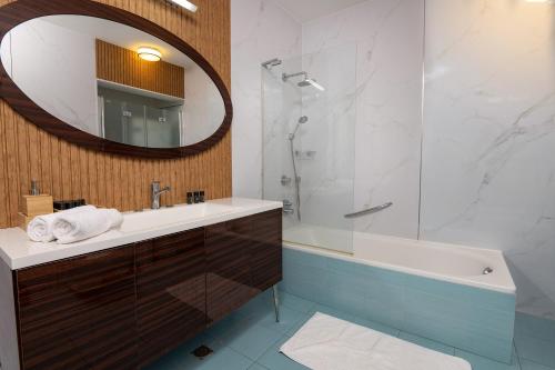 uma casa de banho com um lavatório, uma banheira e um espelho. em Shamyam -שמיים- דירות מהממות על חוף הים עם ג'קוזי פרטי ובריכה במתחם em Netanya