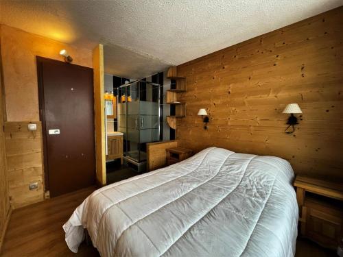 une chambre avec un lit dans un mur en bois dans l'établissement Résidence Peclet - Magnifique appartement 4 pers ski au pied au coeur des Menuires MAE-5454, aux Menuires