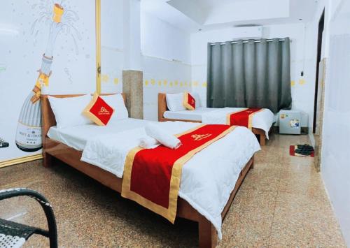 a room with two beds and a chair at Trung Bảo Hotel in Ho Chi Minh City