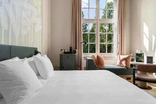 una camera con un letto bianco e una finestra di The College Hotel Amsterdam, Autograph Collection ad Amsterdam