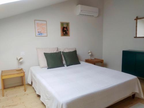 um quarto com uma cama branca e 2 almofadas verdes em Chambre d'hotes du grand st-Marc proche Via Rhona em Sorgues